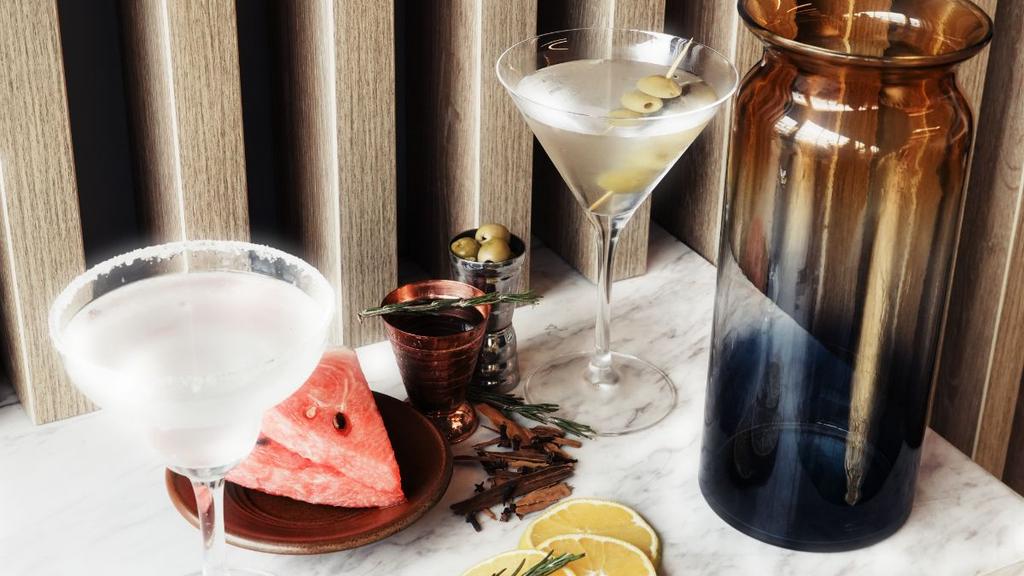 Martinis con aceitunas, sandía, limón y decoración sobre mármol