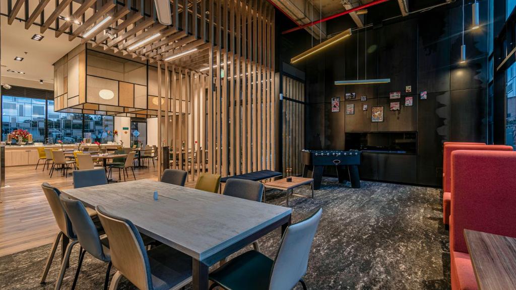 Área con mesas, bancas rojas, futbolín y decoración contemporánea