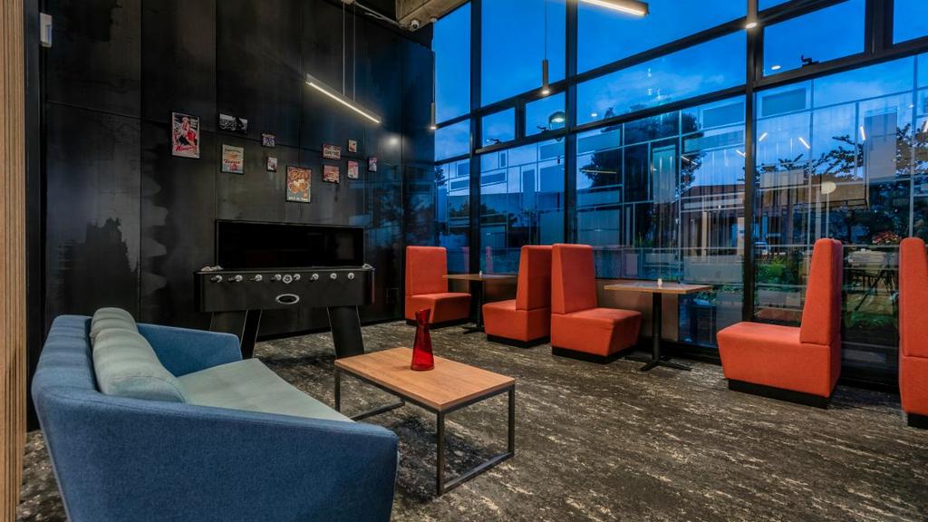 Sala con sofá azul, sillas naranjas, futbolín y decoración contemporánea