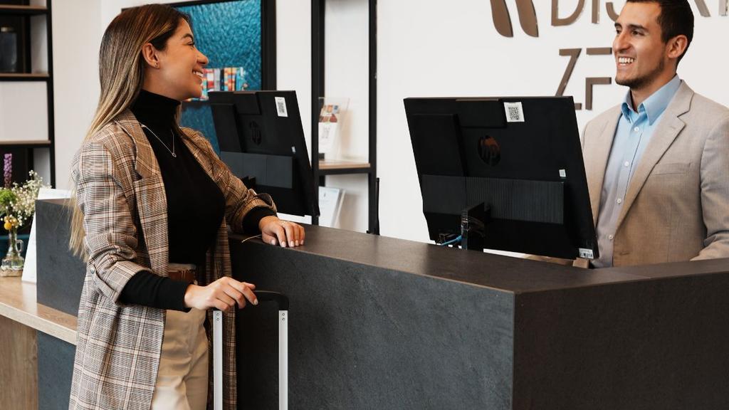 Mujer en recepción moderna conversando con personal del hotel