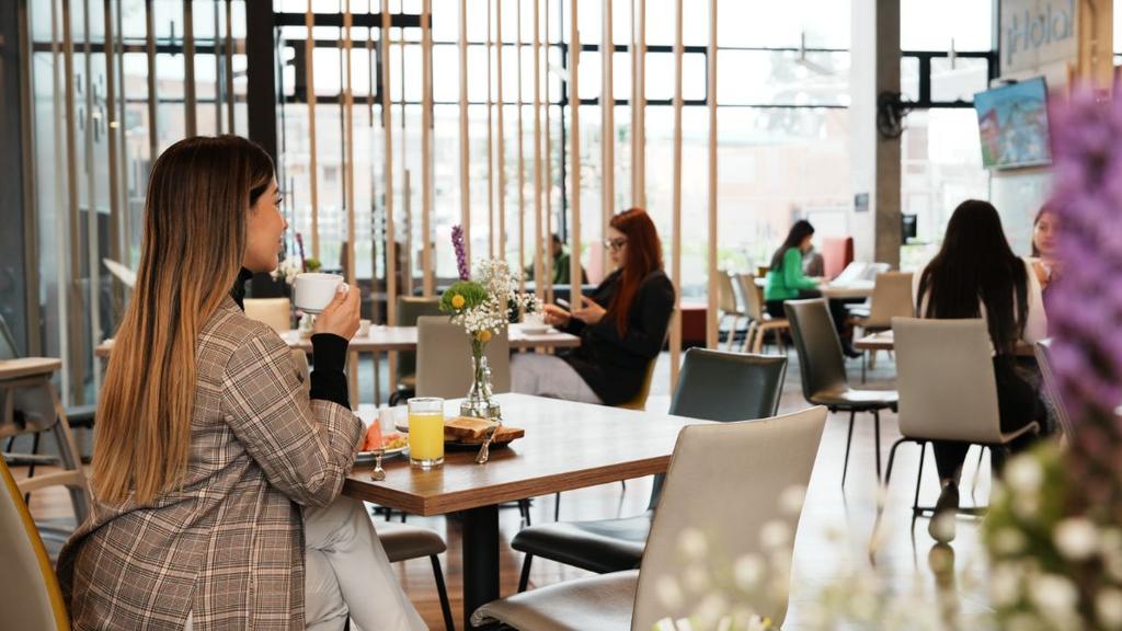 Persona con taza en cafetería moderna con luz natural y decoración acogedora